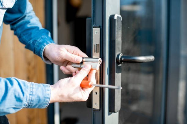 Cerrajero cambiando el cilindro de una cerradura en la puerta de entrada de un departamento