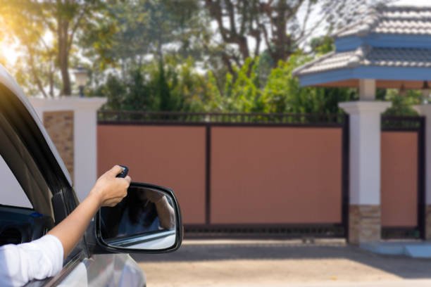 Conductor abriendo el portón de una casa con un telemando desde la ventanilla del auto